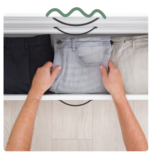 male putting pants away in drawer at home
